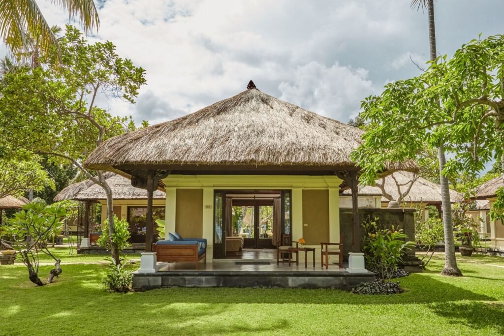 "Exterior view of Deluxe Ocean Villa with thatched roof and lush garden setting."