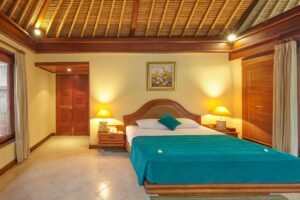 "Spacious villa bedroom with a large bed, warm lighting, and wooden interior."