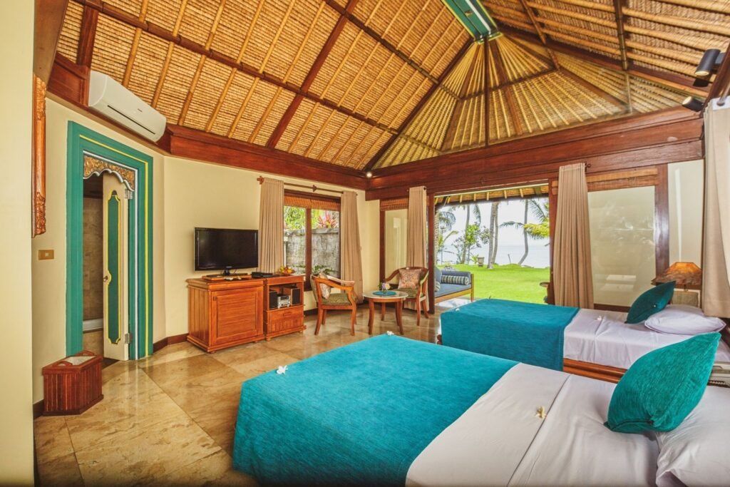 "Tropical-style villa room with work desk, TV, and garden-facing bed."