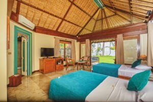 "Tropical-style villa room with work desk, TV, and garden-facing bed."