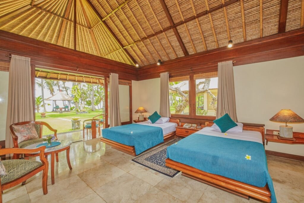 "Villa bedroom with twin beds and wraparound windows offering natural light and garden views."