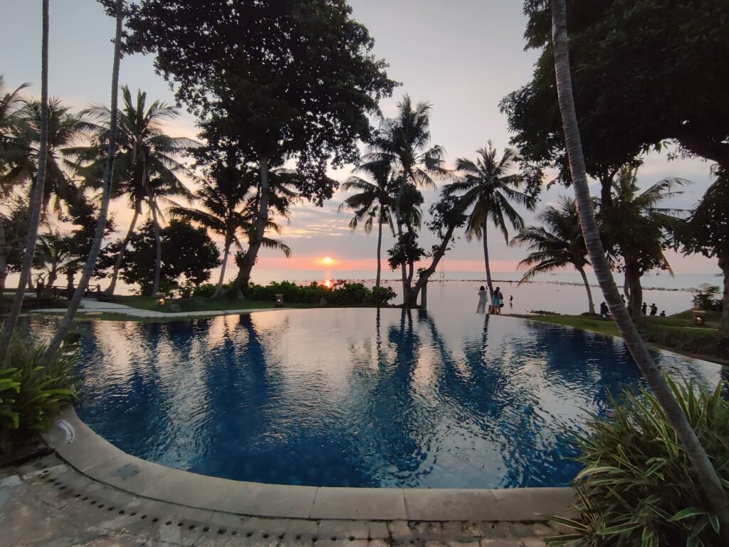 Serene infinity pool reflecting palm trees at sunset, with an ocean view at Puri Bagus Lovina