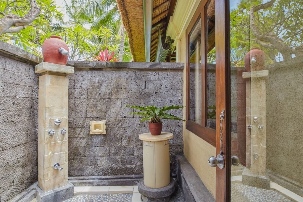 Outdoor-style shower area with stone walls, potted plants, and natural lighting