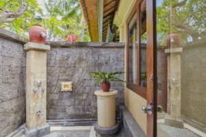 Outdoor-style shower area with stone walls, potted plants, and natural lighting