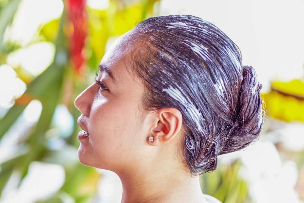 Woman with hair treatment mask applied, looking sideways in a spa environment.