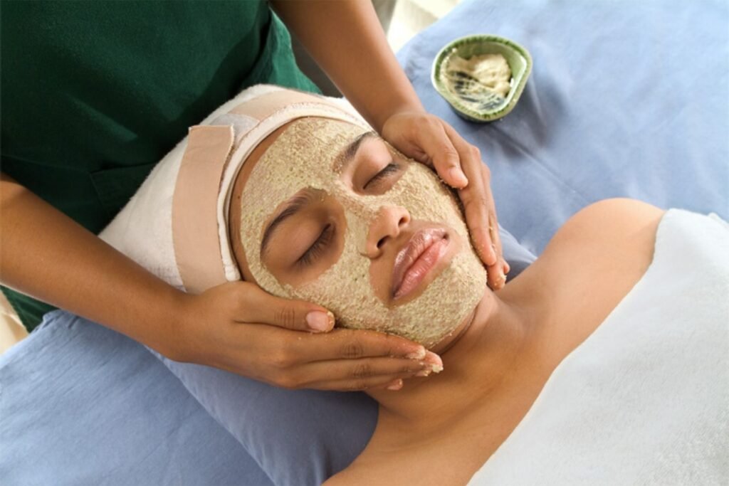 Woman receiving a facial massage with a facial mask applied, eyes closed in relaxation.