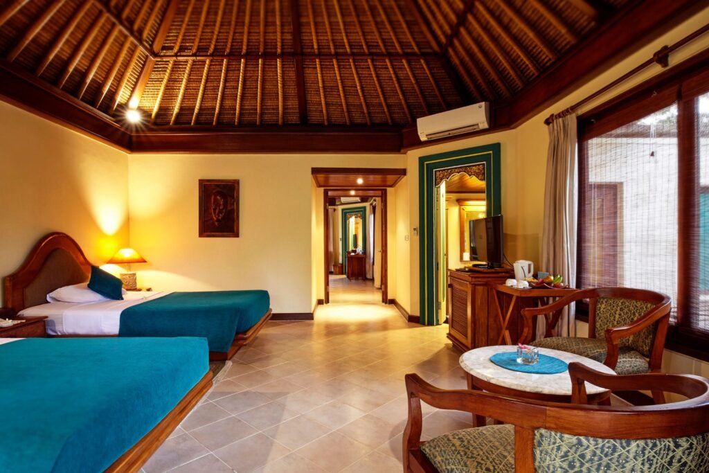 "Tropical-style deluxe room with twin beds, open hallway, and wooden furniture."