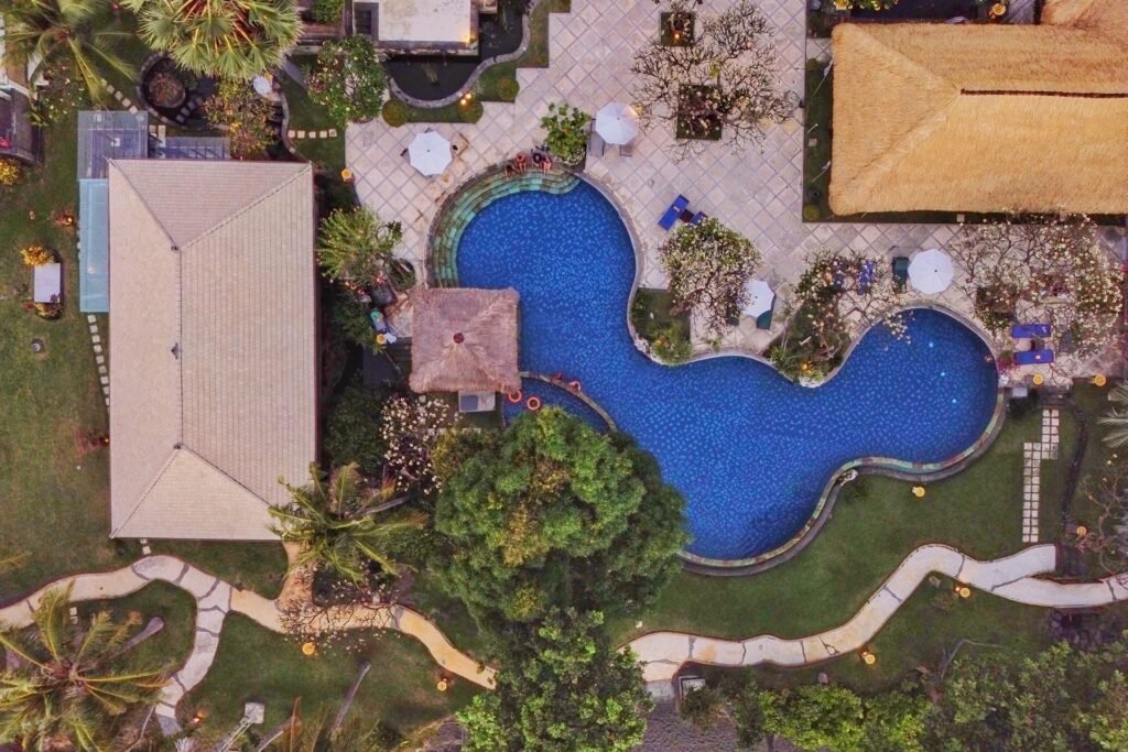 Top-down view of winding swimming pool and lush green landscape at Puri Bagus Lovina