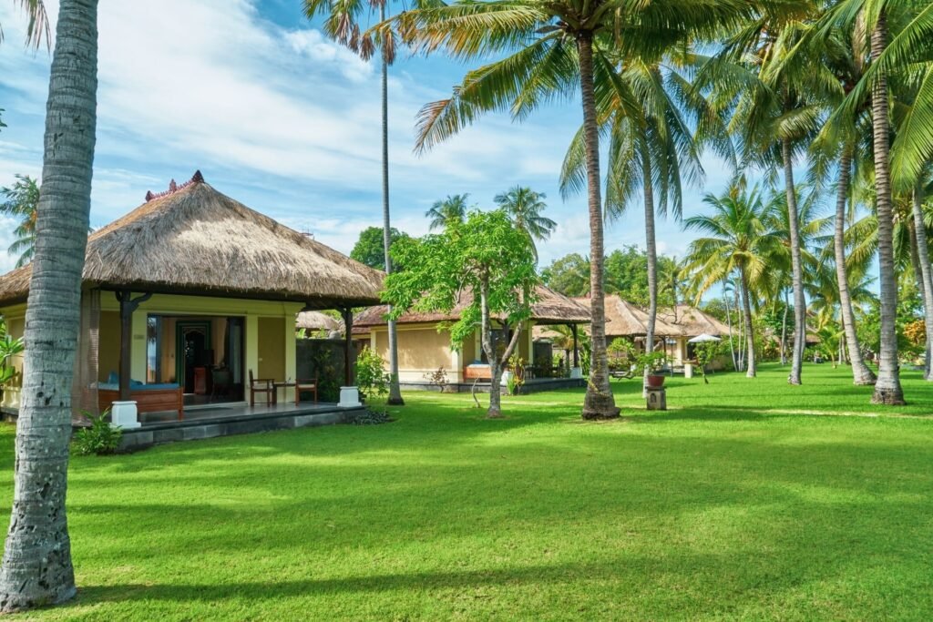 Traditional Balinese villa with coconut trees and manicured lawn at Puri Bagus Lovina