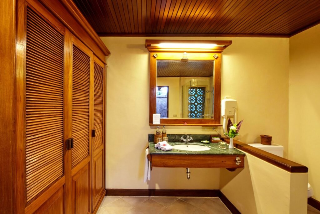Well-lit bathroom featuring a large mirror, wooden cabinet, and modern sink